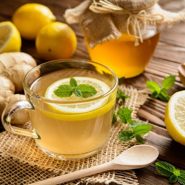 Cup of ginger root tea with lemon, honey and mint on a wooden background